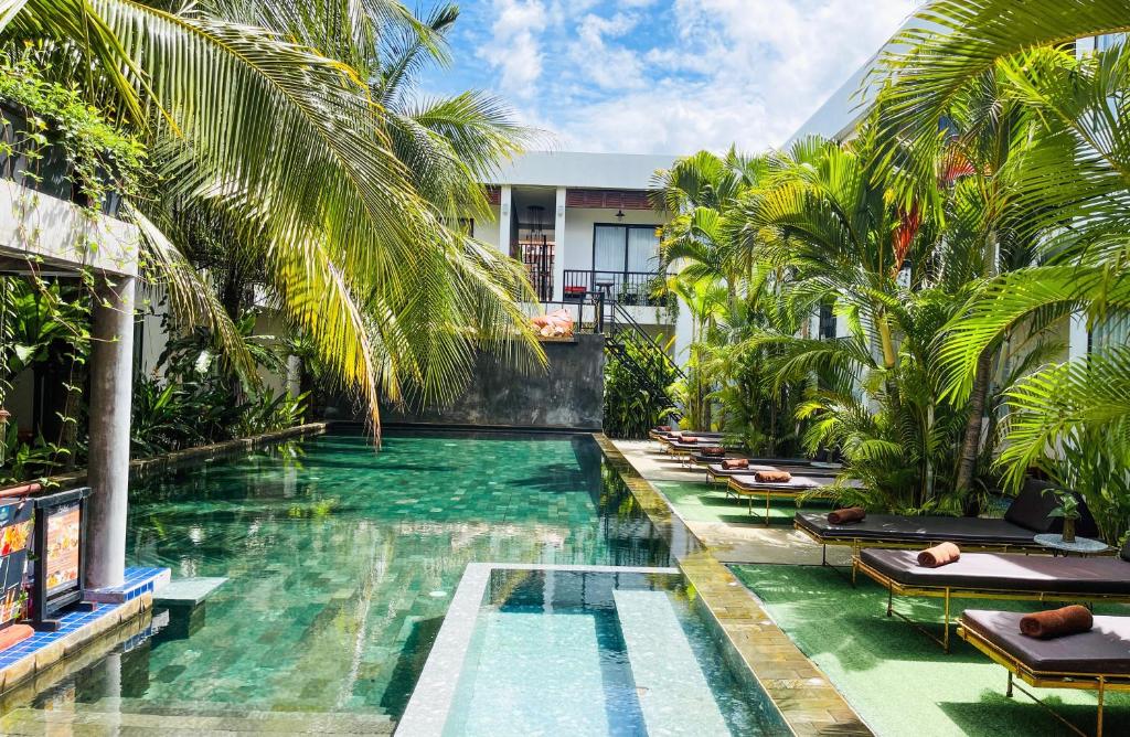 a swimming pool in a resort with palm trees at Central Corner Suite in Siem Reap