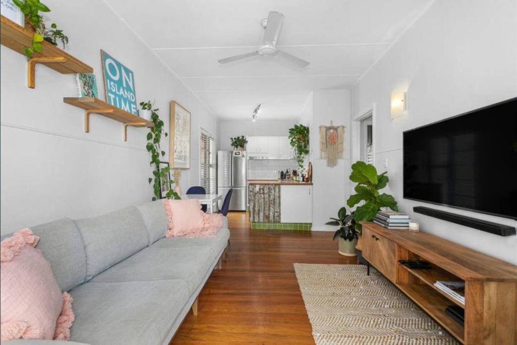 sala de estar con sofá gris y TV de pantalla plana en Beach Pad close to Airport and Iconic Kirra Beach, en Gold Coast