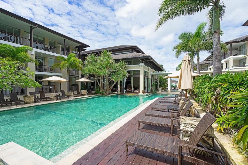 una piscina con sedie e ombrelloni accanto a un edificio di Luxury Resort Studio with Pool - Footsteps to Beach a Casuarina
