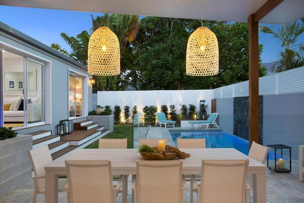 eine Terrasse mit einem Tisch, Stühlen und einem Pool in der Unterkunft Contemporary Coastal Luxury with an Outdoor Pool in Gold Coast