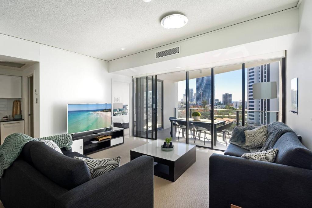 uma sala de estar com 2 sofás e uma televisão de ecrã plano em Luxe High-rise with Al Fresco Dining & Ocean views em Gold Coast