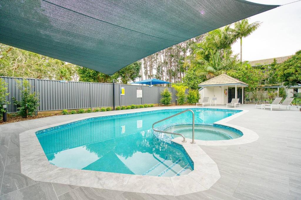 uma piscina com um guarda-chuva azul sobre ela em Poolside Paradise Grove at Burleigh Heads em Gold Coast