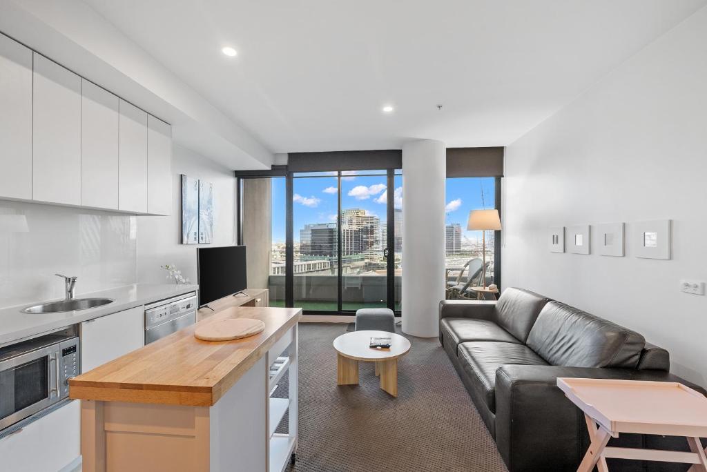 cocina y sala de estar con sofá y mesa en Resort Style Living Yarra Wharf en Melbourne
