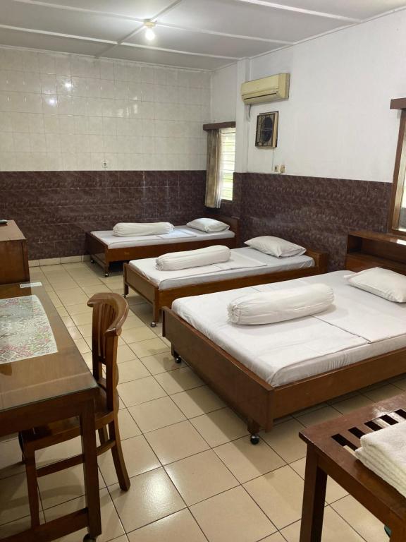 uma fila de camas num quarto com mesas e cadeiras em Hotel Wisma Hasanah em Srondolwetan