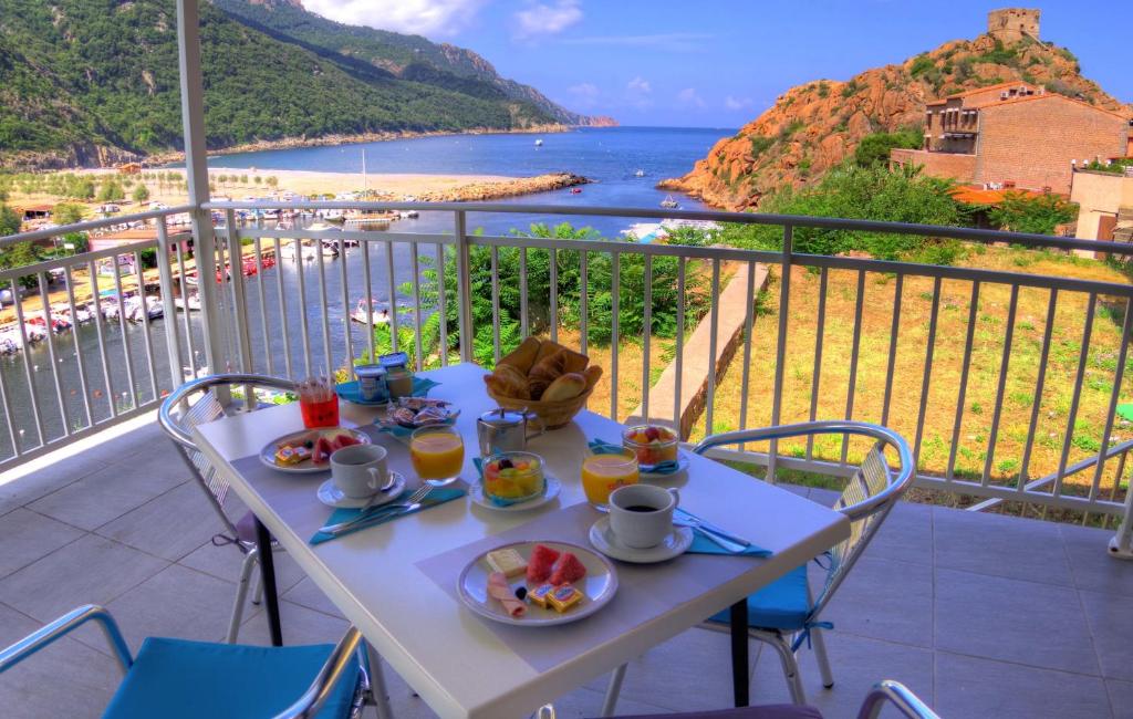 einen Tisch mit Speisen auf einem Balkon mit Meerblick in der Unterkunft Le Méditerranée in Porto Ota