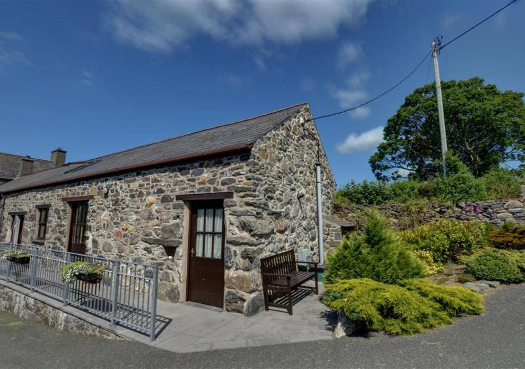 una casa de piedra con un banco delante en Carnedd Llywelyn, en Llanrwst