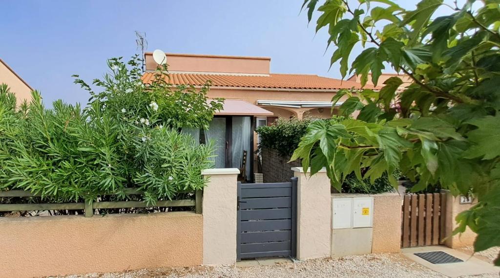 una casa con una valla con una puerta negra en La maison coquillage, en Le Barcarès