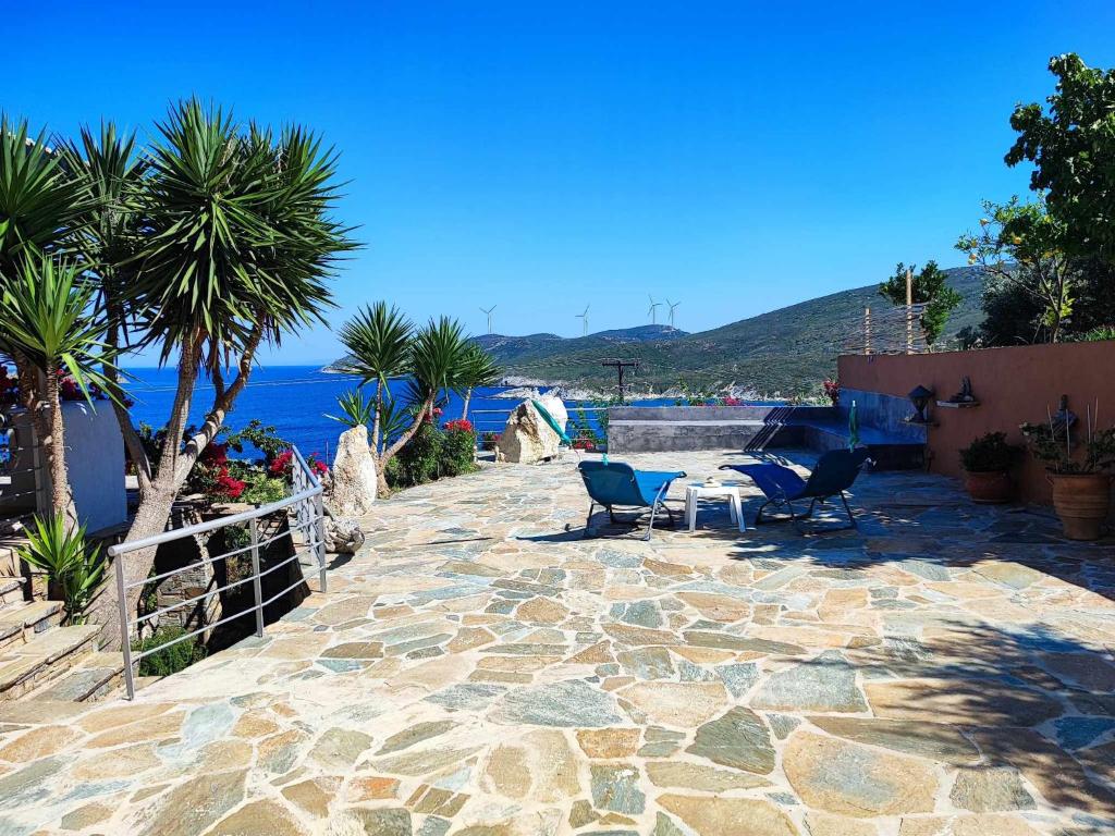 een patio met stoelen en palmbomen en de oceaan bij Seagulls - Within walking distance from sea! in Petriaí
