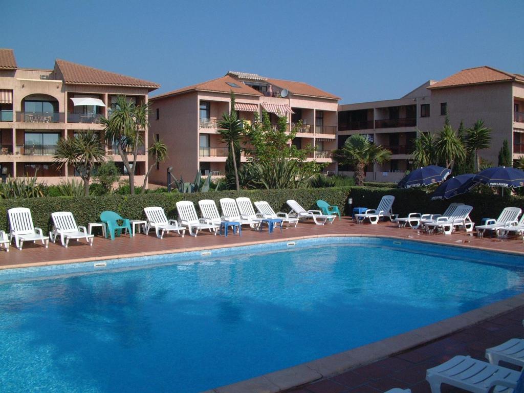 una piscina con tumbonas y un hotel en Résidence les Marines de Moriani Emeraude Locations, en Moriani Plage