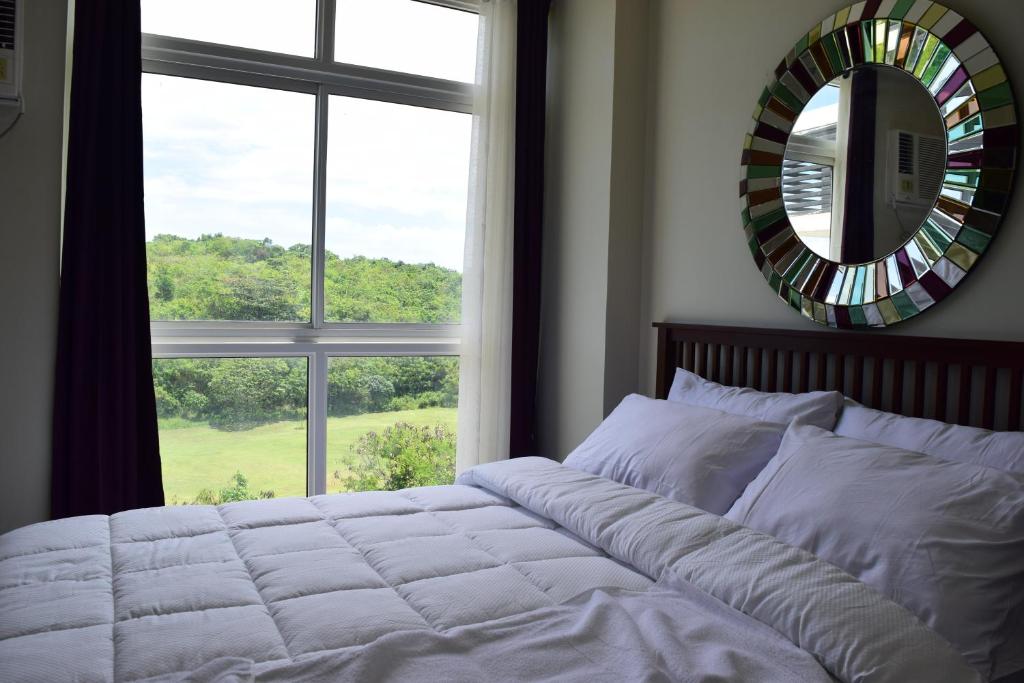 a bedroom with a bed with a mirror and a window at Consuelo Boracay Unit Rental in Boracay