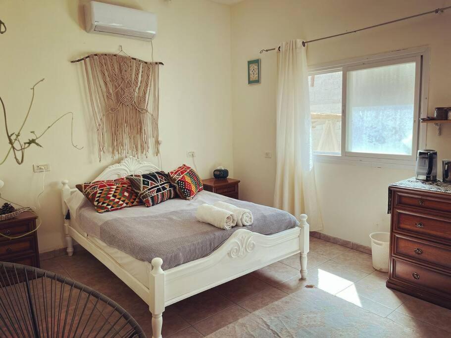 1 dormitorio con cama con almohadas y ventana en יחידת אירוח גלילית, en Hatzor haglilit