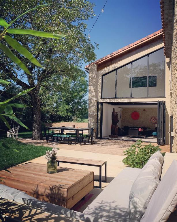 une terrasse avec un canapé, une table et des bancs dans l'établissement Le gîte d ici et d ailleurs Ariège Pyrénées, à Baulou