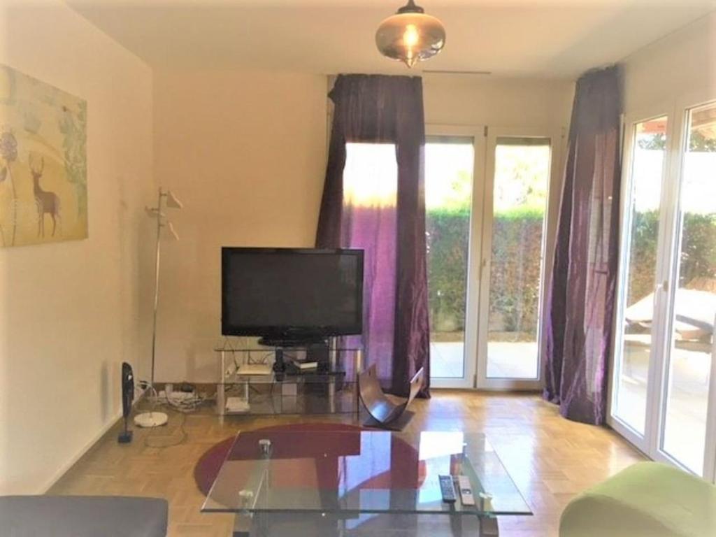 sala de estar con TV y mesa de cristal en Apartment with Garden in Nyon, en Nyon