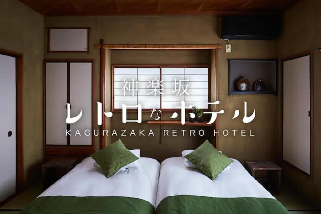 Kagurazaka Retro BAR & HOTEL في طوكيو: سريرين في غرفة مع علامة على الحائط