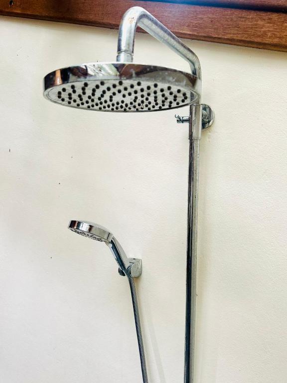 a metal shower head on a white wall at Bambu Huts in Baan Tai