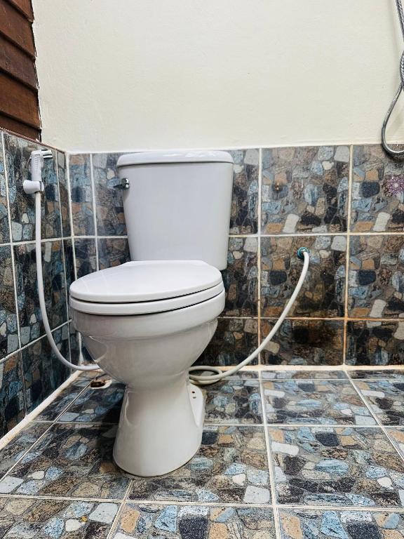 a bathroom with a white toilet in a tiled wall at Bambu Huts in Baan Tai