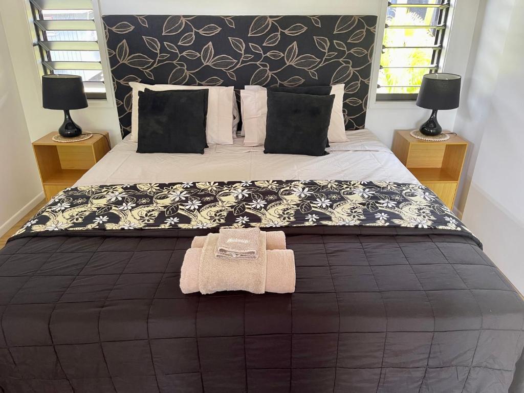 a bedroom with a large bed with a black and white blanket at Rarotonga Villas Absolute Beachfront in Arorangi
