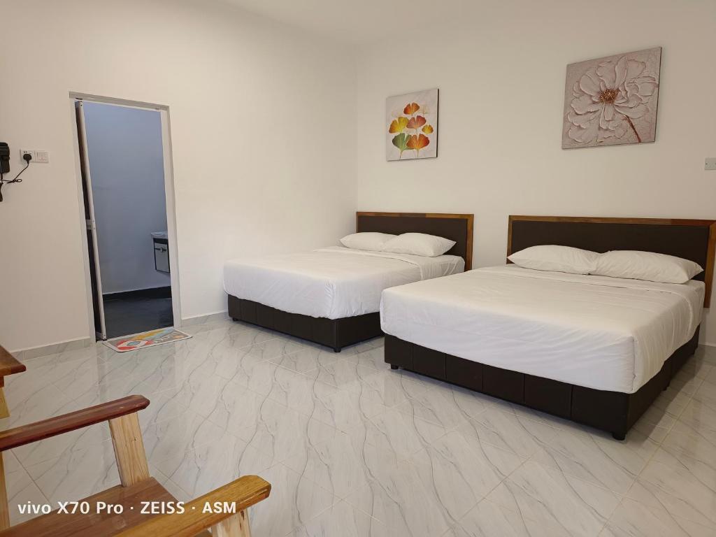two beds in a room with a mirror at ASM Roomstay-4-2 Queen Beds in Kuala Terengganu