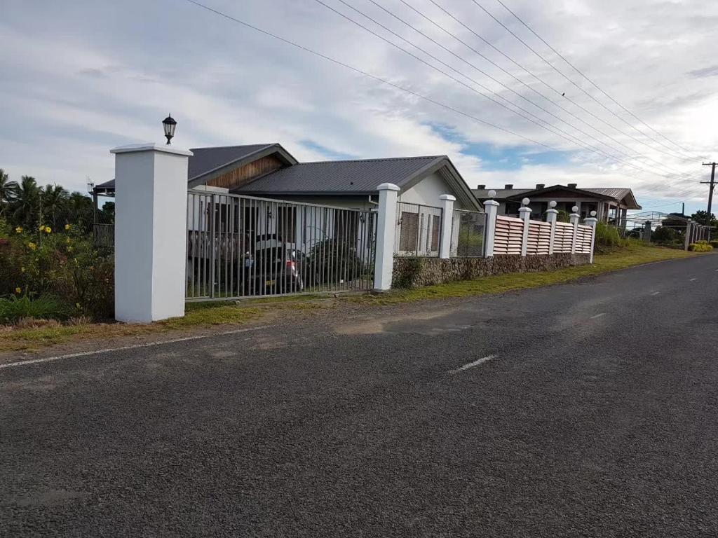 a house with a white fence next to a road at Fiji-Beauty in Nadi
