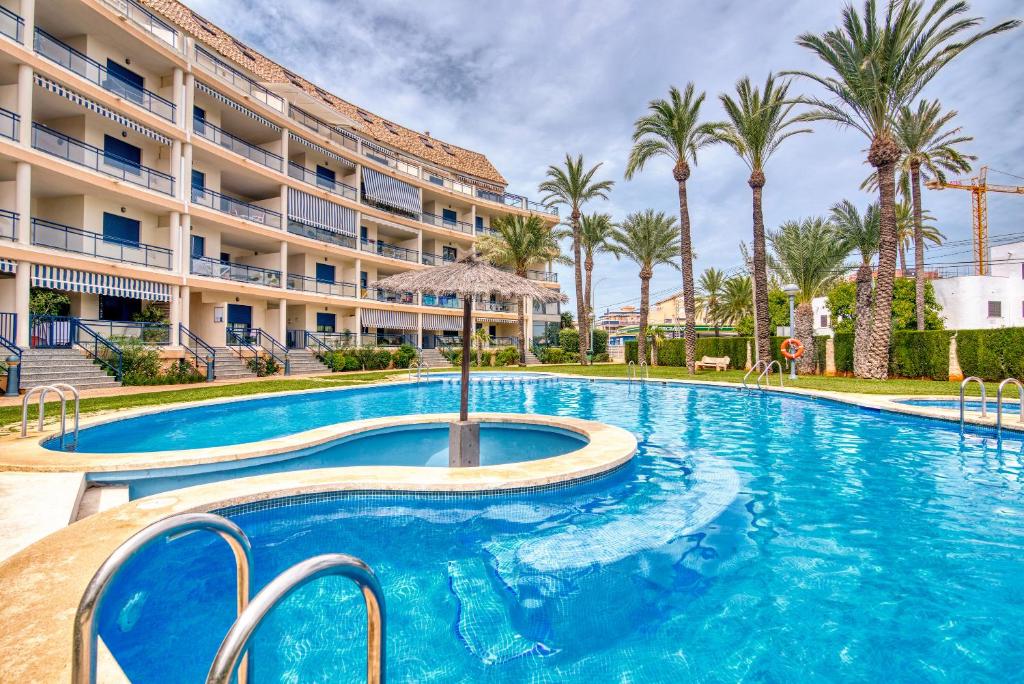 a swimming pool in front of a hotel with palm trees at Sueños de Denia in Denia