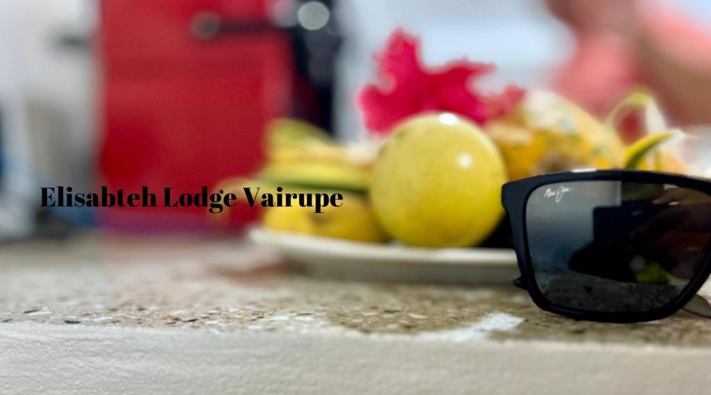 occhiali da sole neri seduti su un bancone con un piatto di frutta di Elisabeth Lodge Vairupe a Bora Bora