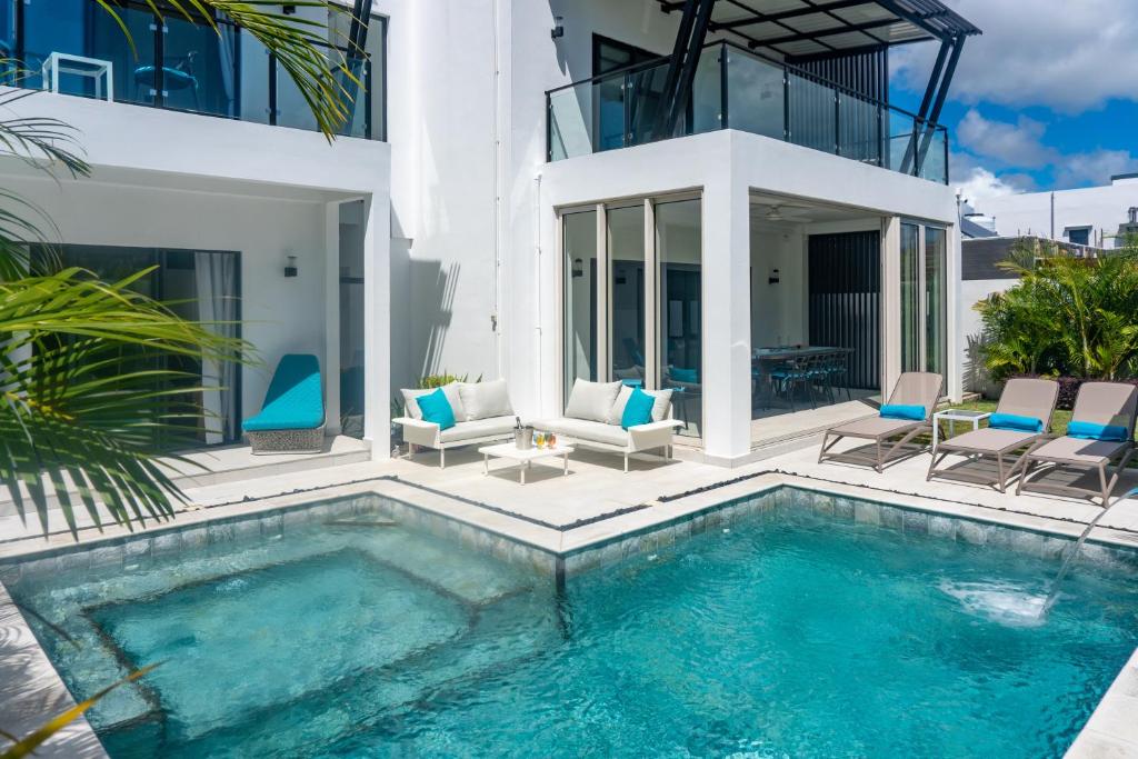 a swimming pool with chairs and a house at Pearl Collection in Grand-Baie