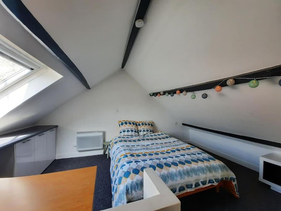 een slaapkamer op zolder met een bed en een raam bij Charmante maison 3 chambres avec cour in Lille