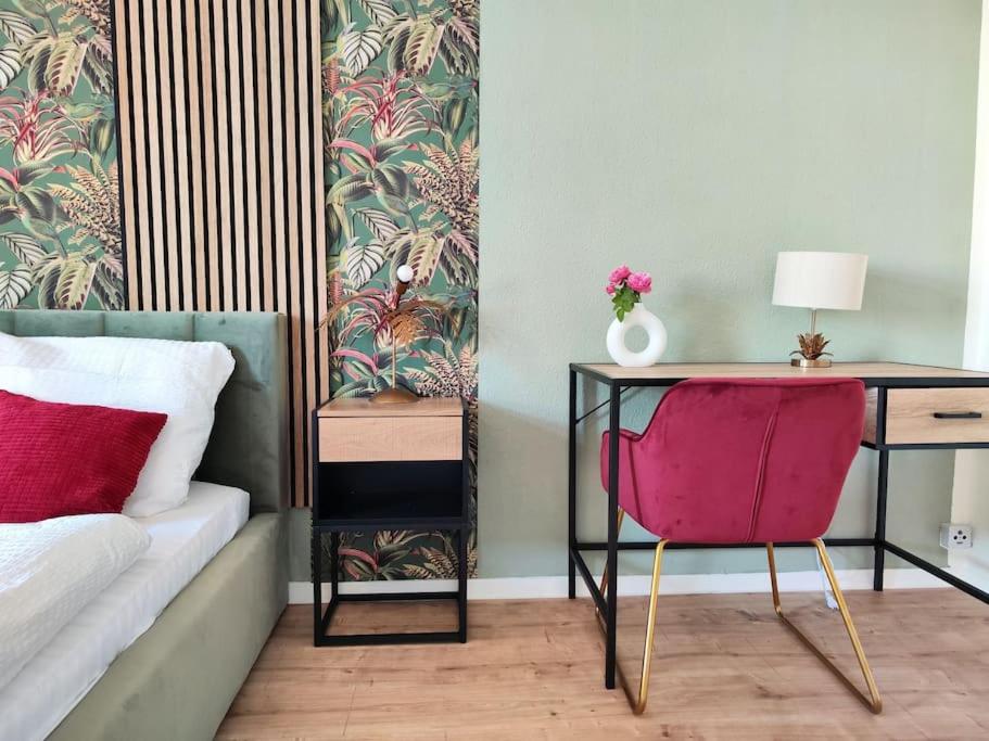 Schlafzimmer mit einem Schreibtisch und einem Bett mit einem rosa Stuhl in der Unterkunft tealounge 2 Raum + Küche in Dresden