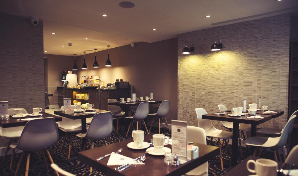 um restaurante com mesas e cadeiras num quarto em Best Western Plus Delmere Hotel em Londres