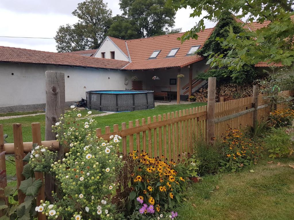 een hek voor een huis met bloemen bij Apartmán na farmě u koní in Milešov