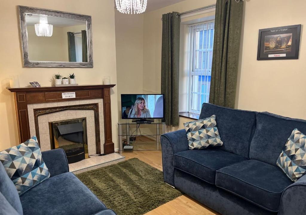 a living room with a blue couch and a television at 3 Bedroom Apartment, Ballymena, The Wee Stop Gap in Ballymena