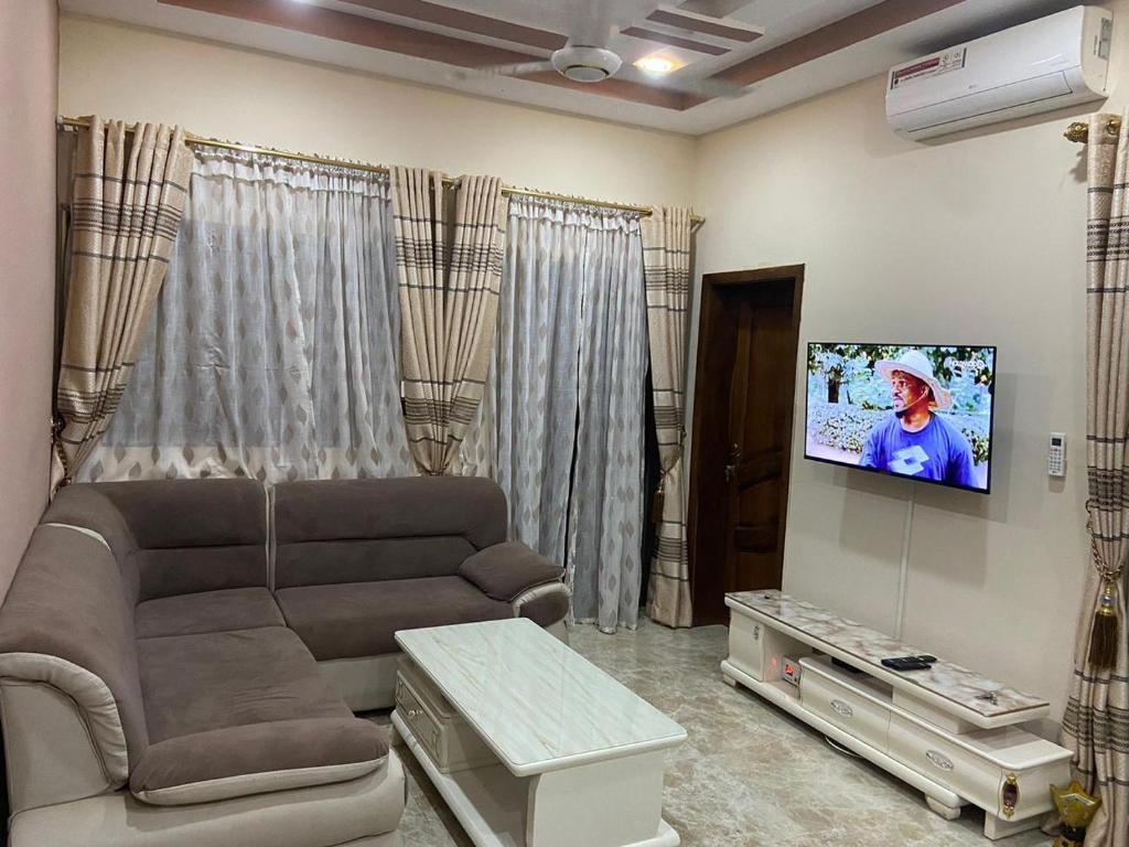 uma sala de estar com um sofá e uma televisão de ecrã plano em Coyimo em Ouagadougou