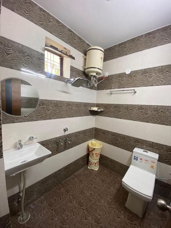 une salle de bains avec lavabo, toilettes et miroir dans l'établissement Skylight homestay, à Dehradun