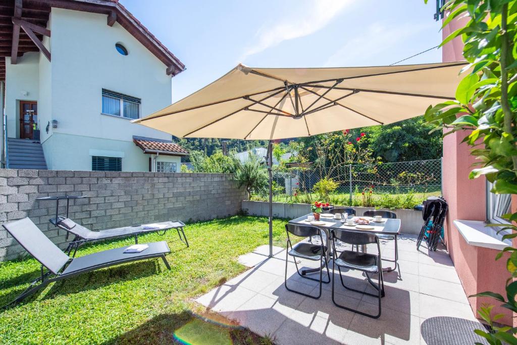 un patio con sombrilla, mesa y sillas en Casa Carolina 1 and Casa Carolina 2 - Happy Rentals, en Losone