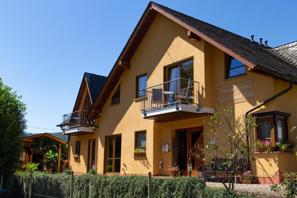 una casa gialla con due balconi e una recinzione di Wein- und Gästehaus Michels a Wolf