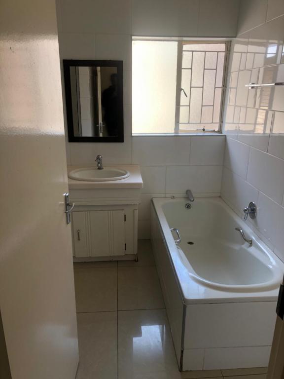 biała łazienka z wanną i umywalką w obiekcie The Coastal Guesthouse w mieście Vanderbijlpark
