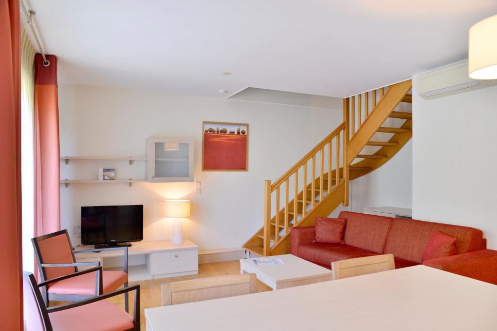 sala de estar con sofá rojo y escalera en Adonis Divonne-Les-Bains Résidence Du Lac, en Divonne-les-Bains