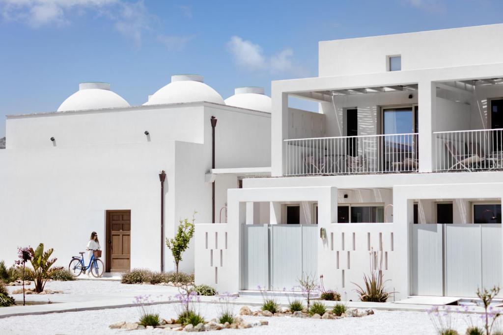 une femme faisant du vélo devant un bâtiment blanc dans l'établissement ALERÓ Seaside Skyros Resort, à Skiros