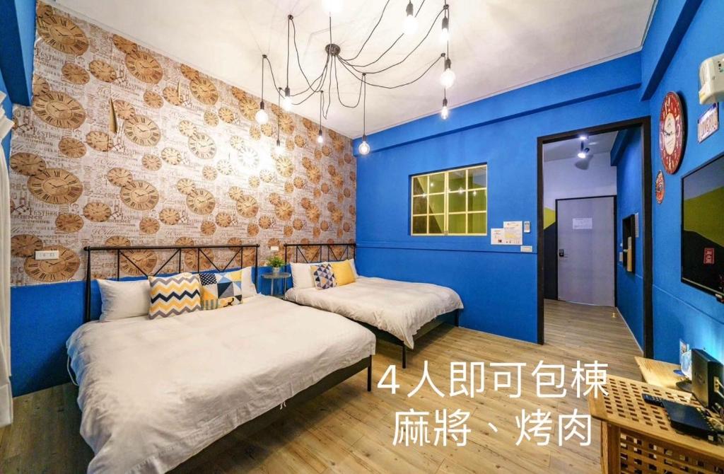 two beds in a room with blue walls at Tainan Little Day in Tainan