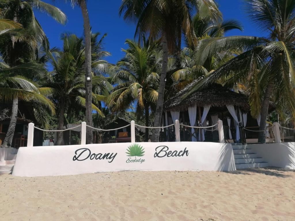a sign on the beach with palm trees in the background at Doany Beach in Antafondro