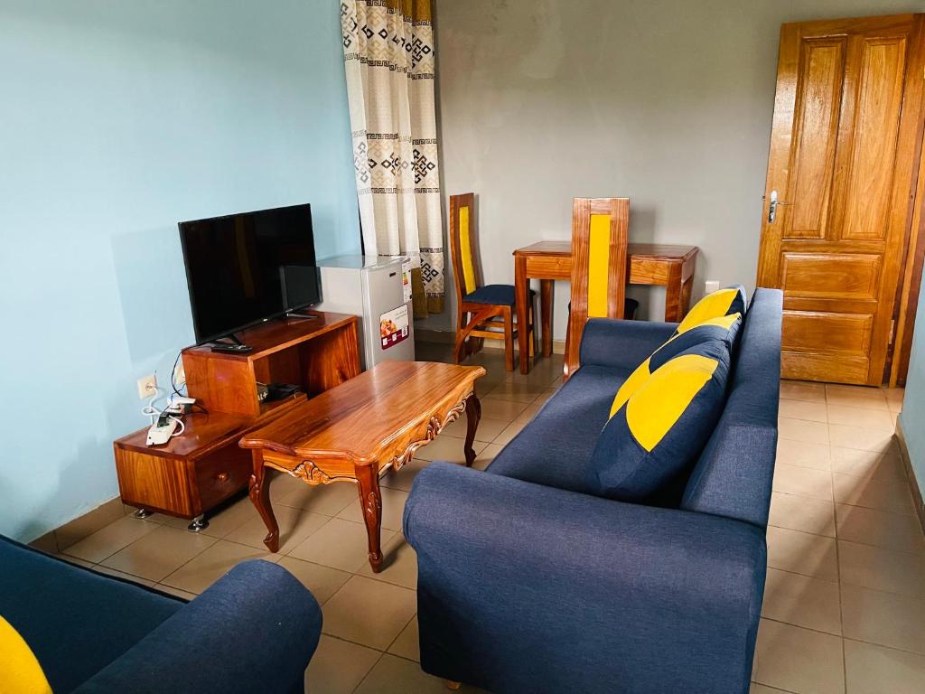 a living room with a blue couch and a tv at Complexe BEL AIR in Bafoussam