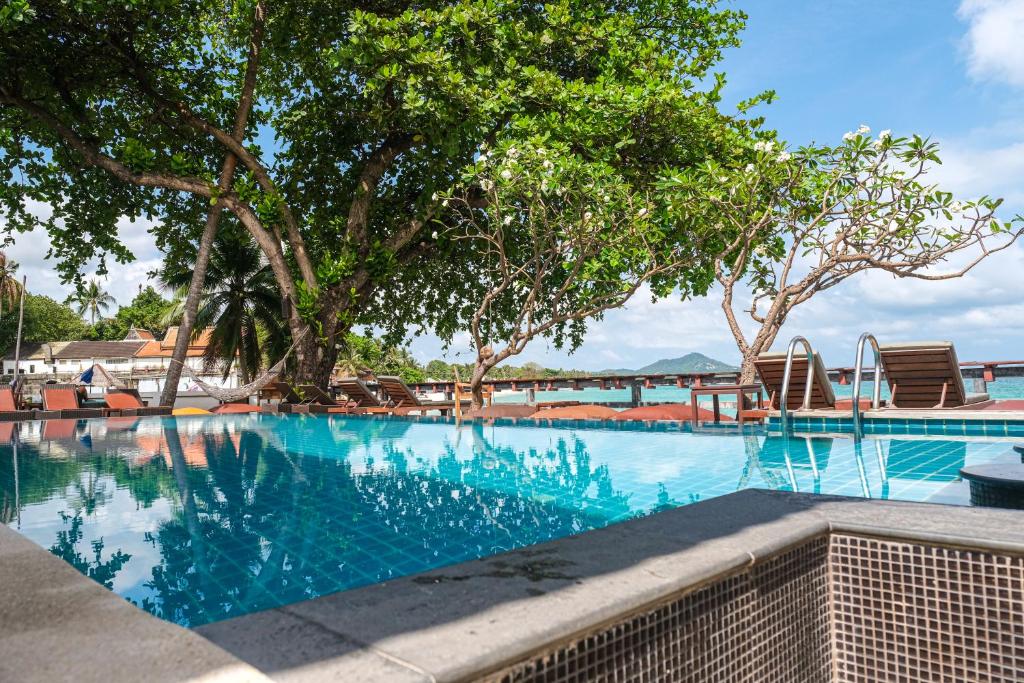 a swimming pool with blue water and trees and chairs at Bhundhari Chaweng Beach Resort Koh Samui - SHA Plus in Chaweng