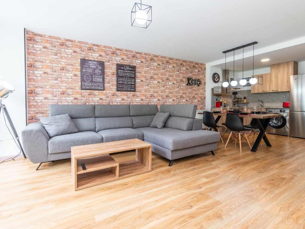 a living room with a couch and a brick wall at Increibles Vistas Al Valle De Arinsal NY - A Pie De Pistas - Parking Incluido in Arinsal