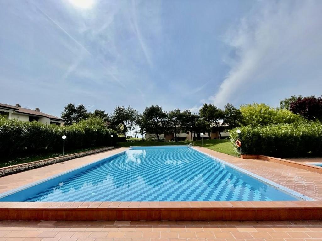 a large swimming pool with blue water in a yard at il lauro apartment in Lazise