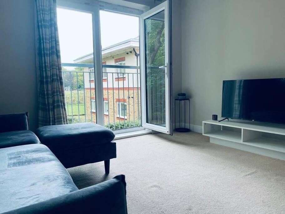 een woonkamer met een bank en een groot raam bij Gatwick Airport Apartment in Crawley