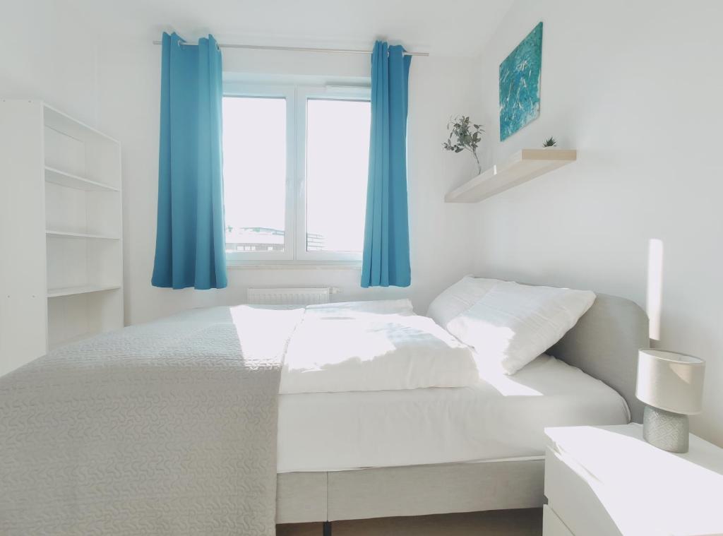 1 dormitorio blanco con cortinas azules y 1 cama en Dobrego Pasterza 120D by Homeprime, en Cracovia