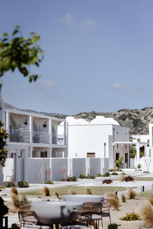 a white building with tables and chairs in front of it at ALERÓ Seaside Skyros Resort in Skiros