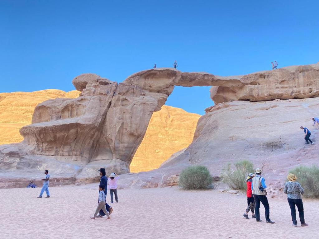 a group of people walking in front of an arch at Wadi Rum fun camp in Wadi Rum