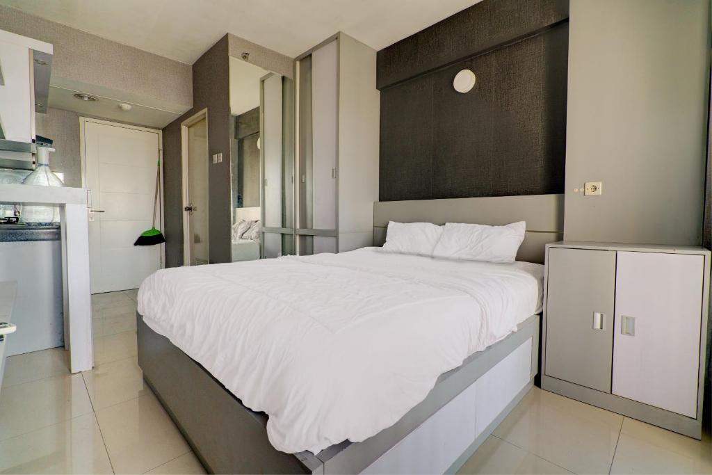 Cette chambre comprend un grand lit blanc et une cuisine. dans l'établissement OYO Life 92889 Apartement Grand Sentraland Karawang By A.t Room, à Karawang