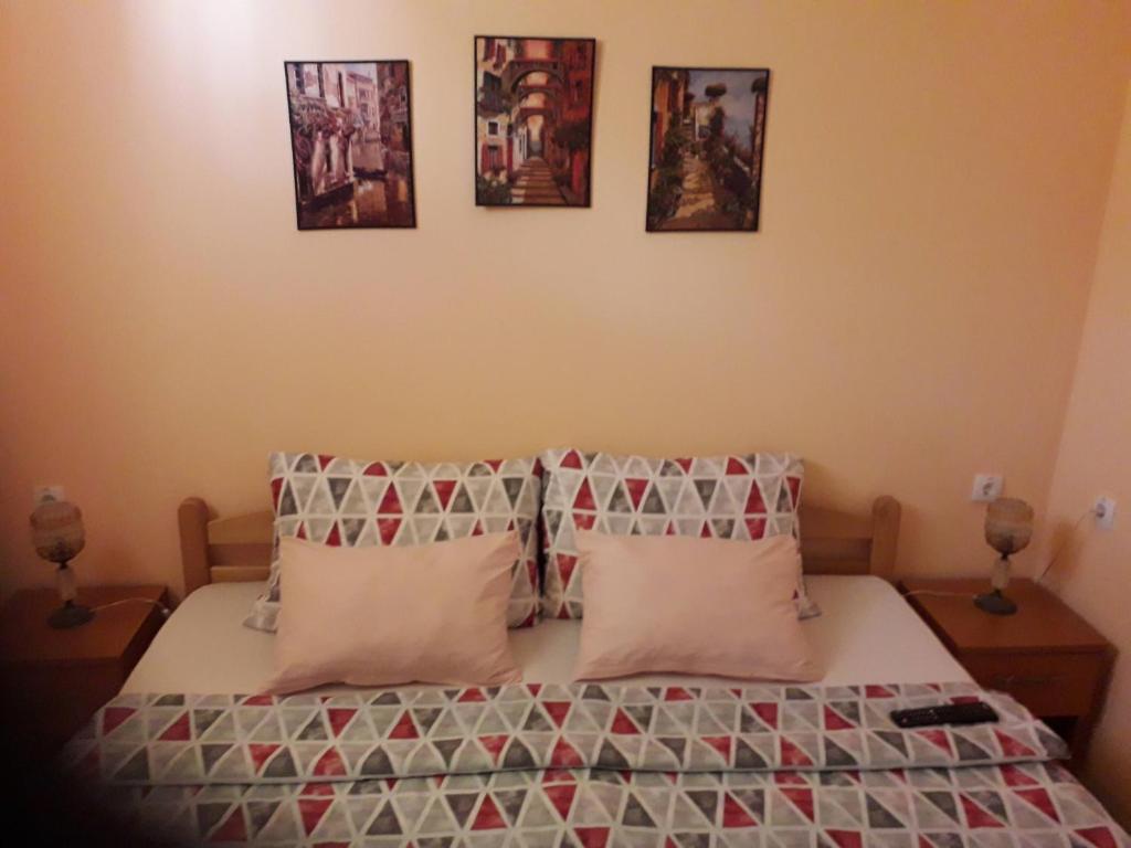 a bedroom with a bed with four pictures on the wall at VILANATALIJA PANSION, APATIN in Apatin